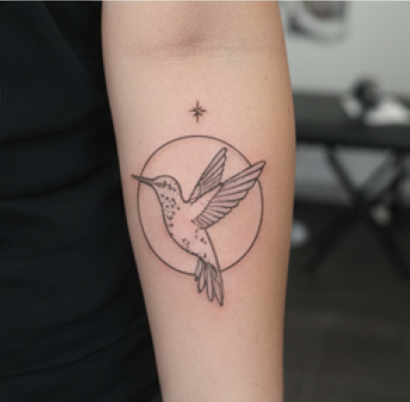 kädessä tatuointi lentävästä linnusta taustalla ohut rengas ja yläpuolella siro tähti